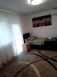 a bedroom with a bed and a window with white curtains at Dedin dvorac in Valpovo