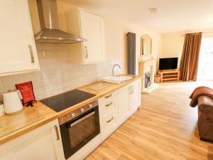 a kitchen with white cabinets and a stove top oven at Willow Cottage in Barrow upon Humber