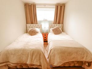 two beds in a small room with a window at Willow Cottage in Barrow upon Humber
