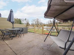 a patio with a table and chairs and an umbrella at Willow Cottage in Barrow upon Humber