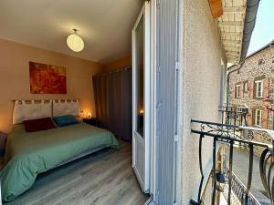 a bedroom with a bed and a door to a balcony at Maison de bourg près du château in Polignac