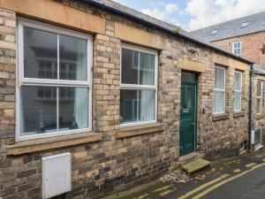 ein Backsteingebäude mit grüner Tür und Fenstern in der Unterkunft The Bungalow in Whitby