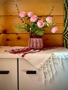 a vase of pink roses sitting on top of a counter at Căsuțele dintre vii in Runcu
