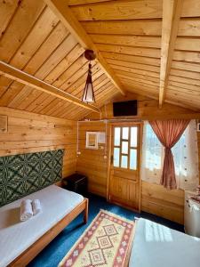 a bedroom in a wooden cabin with two beds and a window at Căsuțele dintre vii in Runcu +33 photos