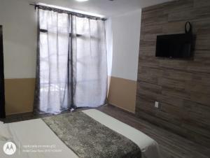 a bedroom with a bed and a tv and a window at Hotel Casa Tepic in Tepic