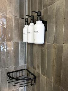 tre bottiglie bianche su una parete in un bagno di Lefkada City Escape a Città di Lefkada