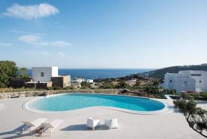 a swimming pool with chairs and a view of the ocean at The Mykonian Escape in Mikonos