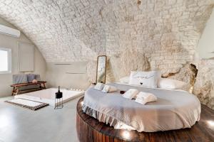 a bedroom with a large bed with a stone wall at MALOLÙ luxurysuite in Ostuni +29 photos