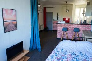 salon z łóżkiem oraz kuchnia z niebieskimi zasłonami w obiekcie Appartement bord de vilaine, proche centre et gare w mieście Redon