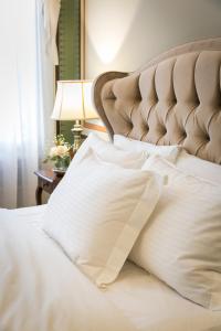uma cama com lençóis brancos e almofadas em Boutique Hotel 1905 em Xanthi