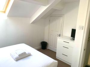 a white bedroom with a bed and a tv at West Street Mews - Serviced Accommodation in Exeter