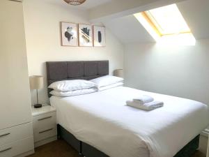 a bedroom with a white bed with two towels on it at West Street Mews - Serviced Accommodation in Exeter