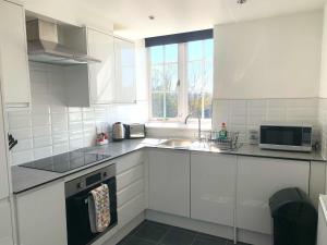 a white kitchen with a sink and a microwave at West Street Mews - Serviced Accommodation in Exeter