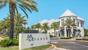 a sign in front of a building with palm trees at Seacrest Townhomes 7 - Sol and Sea in Seacrest