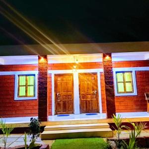 a red brick house with wooden doors at night at Patil villa in Nagaon