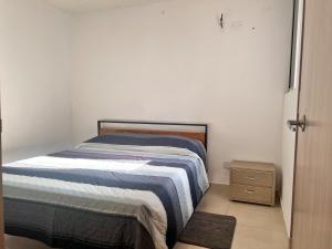 a small bedroom with a bed and a night stand at Max House 503 in Soledad +4 photos