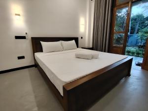 a bedroom with a large bed with white sheets and a window at Cloud9 villa weligama in Weligama