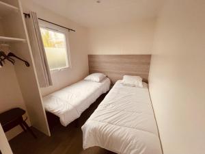 two beds in a small room with a window at Mobil Home Oliviers 2 in Valras-Plage