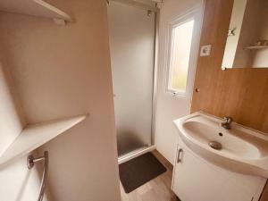 a white bathroom with a sink and a mirror at Mobil Home Oliviers 2 in Valras-Plage