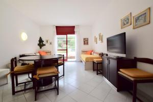 a living room with a table and a couch and a television at Appartamento in residence con piscina in Marina di Bibbona