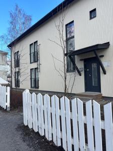 a white picket fence in front of a house at Foliate Living Taimi in Jyväskylä