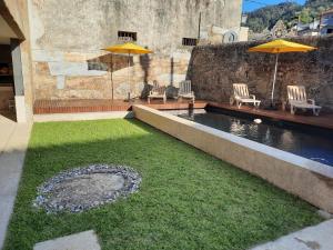 a swimming pool with two chairs and two umbrellas at O Refúgio - Gerês in Souto