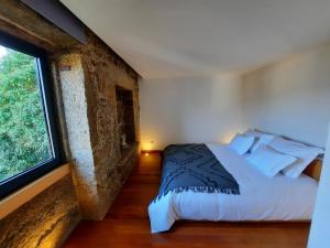 a bedroom with a bed and a large window at O Refúgio - Gerês in Souto +18 photos