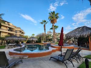 a pool with chairs and umbrellas and palm trees at Beach Eateries 10 min walk 1BDRM Golf view in San José del Cabo