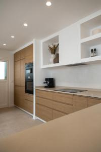 cocina con paredes blancas y armarios de madera en Villa Hondartza Corralejo, en Corralejo