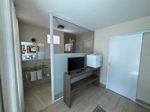 a bathroom with a television on a table with a mirror at Pousada Familiar Vilage Bed & Breakfast Homestay in Volta Redonda