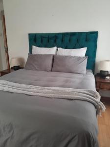 a large bed with a blue headboard and white pillows at InaLups Stay in Roodepoort