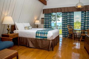 1 dormitorio con 1 cama, mesa y sillas en Silver Dart Lodge, en Baddeck