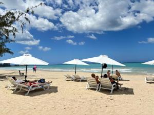 personas sentadas en sillas en una playa con sombrillas en Bali Hotel Adults Only Isla Verde, a Trademark by Wyndham, en Carolina