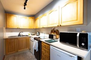 a kitchen with wooden cabinets and a microwave at KATHERINES COURT - Spacious Apartment with Rolling Hill Views in Kendal