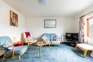 a living room with chairs and a flat screen tv at KATHERINES COURT - Spacious Apartment with Rolling Hill Views in Kendal