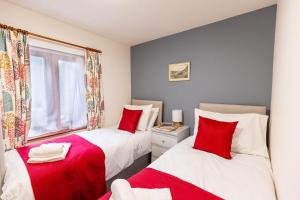 two beds in a room with red and white at KATHERINES COURT - Spacious Apartment with Rolling Hill Views in Kendal