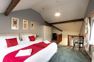 a bedroom with a large white bed with red pillows at KATHERINES COURT - Spacious Apartment with Rolling Hill Views in Kendal