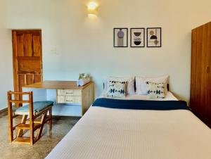 a bedroom with a bed and a desk and a chair at Evaddo Homes in Mandrem