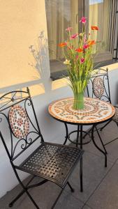 a table and chairs with a vase of flowers on it at TRIO apartment in Piešťany