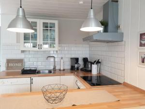 a kitchen with white cabinets and a sink and lights at Ferienhäuser Dornumersiel in Dornumersiel