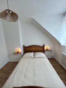 a bed in a white room with two lamps at La maison du Distillateur in Plurien