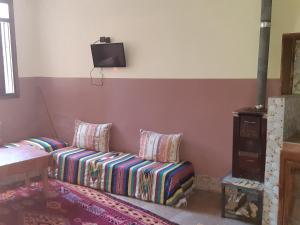 a living room with a couch and a tv on the wall at Auberge De La Vallée in Imlil