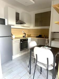 een keuken met een tafel, stoelen en een koelkast bij Joli Studio près de la mer in Toulon
