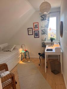 a bedroom with a bed and a desk and a window at Bo nära strand och city. in Västra Frölunda