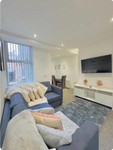 a living room with a blue couch and a tv at Room 4 Shared House in L6 in Liverpool