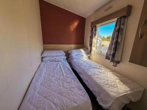 BenacreにあるHomely Caravan At Kessingland Beach Holiday Park, Suffolk Ref 90040Bcの窓のある小さな部屋にベッドが2つある +13枚の写真
