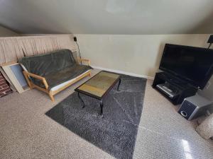 a living room with a chair and a television at Suites On Chocolate - The Hershey House in Hershey +3 photos