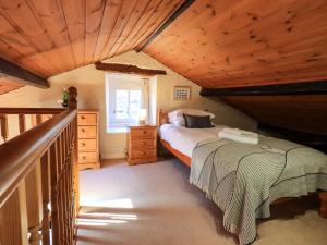 a bedroom with a bed and a wooden ceiling at Courtyard Cottage in Ambleside