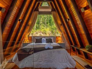 ein Bett in einem Zimmer mit einem großen Fenster in der Unterkunft Cabana Memórias in Gramado + 89 Fotos