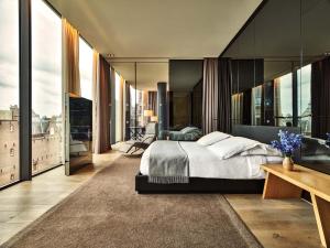 a bedroom with a large bed and large windows at Conservatorium Hotel in Amsterdam